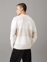 Sweater Calvin Klein de punto de algodón a rayas horizontales en tonos beige y blanco, con logo CK bordado en el pecho.