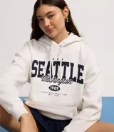 Saco cerrado tipo hoodie blanco con capucha, cordón ajustable, bolsillo canguro y estampa frontal con el texto "SEATTLE Washington 1989".
