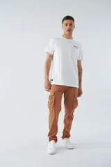 Pantalón cargo color marrón, corte slim, con cierre y botón en la cintura, pasacintos y bolsillos cargo con botones.
