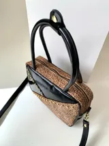 Cartera rígida negra de cuero con tachas plateadas y tres combinaciones de cuero diferentes que aportan textura. Tiene herrajes y cierre metálico plateado marca YKK. Cuenta con un asa fina para llevar al hombro o en la mano y una correa larga extra regulable.