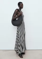 Vestido largo de punto fino, con tirantes anchos y cuello caja. Presenta un estampado de rayas verticales en blanco y negro, y un bajo asimétrico.