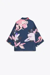 Camisa azul con estampado de flores rosas, cuello solapa y manga corta.