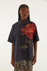 Camisa negra con estampado floral rojo, corte suelto, cuello clásico, cierre frontal con botones y mangas cortas.
