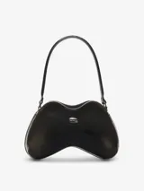 Bolso de hombro con forma orgánica tridimensional, similar a un control de videojuego, en material rígido soft-touch negro. Cuenta con un remache metálico ovalado en el frente y correa fija para llevar al hombro.