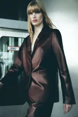 Blazer de cuero color marrón chocolate con cuello solapa, cierre frontal con dos botones, bolsillos de vivo y abertura en la espalda.