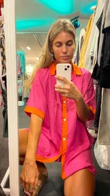 Camisola con diseño color fucsia y detalles en naranja, de corte holgado y botones frontales.