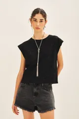 Remera negra de jersey con glitter, detalles en tela base en el frente y medallita marcaria en la espalda.
