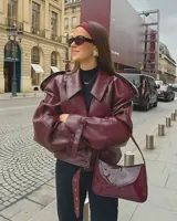 Campera corta de cuero sintético color borgoña, con cuello solapa, corte oversize, cierre cruzado con hebillas y cinturón.