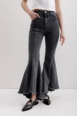 Pantalón de jean gris elastizado con corte ajustado en la parte superior y volados en la parte inferior de la pierna. Tiene ruedo irregular con terminación descosida.