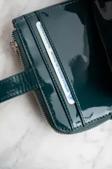 Billetera de cuero vegano color petróleo con cierre y compartimentos para tarjetas.