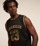 Musculosa deportiva de baloncesto negra con detalles en amarillo, confeccionada en tejido texturizado con tecnología dry fit. Presenta estampado frontal con la inscripción "Los Angeles" y el número 23.