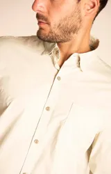 Camisa amarilla de algodón orgánico, manga larga con botones de madera, cuello italiano, calce regular, bolsillo de pecho con logo bordado.