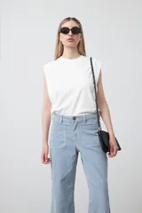 Pantalón de mujer de tiro medio, pierna amplia y recta, confeccionado en tela de algodón a rayas verticales finas celestes y blancas. Presenta bolsillos utilitarios grandes en la parte delantera.