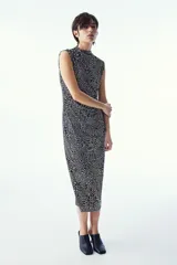 Vestido midi negro con estampado de manchas blancas, sin mangas, de punto elástico, corte ajustado, cuello alto y costura curva fruncida en un lateral para conseguir un efecto drapeado que realza la figura.