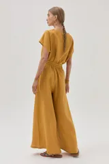 Pantalón de lino color mostaza, de corte palazzo, con lazo en la cintura, pinzas en el frente y bolsillos laterales.