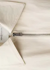 Chaqueta color crema con cierre frontal con cremallera, cuello camisero, manga larga y diseño oversize.