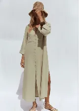 Vestido camisero largo color verde oliva, confeccionado en lino liviano, con cuello camisero, mangas largas con puños abotonados, cierre frontal con botones y aberturas laterales en el ruedo.