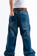 Pantalón de jean azul desgastado, corte mega baggy, con estampa serigrafiada en la pierna y botones personalizados.