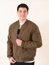 Chaqueta tipo bomber color verde militar, con cierre frontal, cuello y puños acanalados. Presenta bolsillo utilitario con cierre en la manga izquierda y bolsillos frontales con solapa y broche.