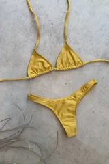 Conjunto de bikini verde esmeralda, con corpiño triangular de atar al cuello y espalda, con almohadillas desmontables, y bombacha colaless con laterales fijos.
