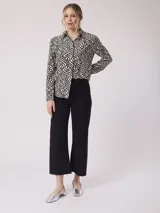 Camisa de manga larga con estampado de cebra en tonos beige, marrón y lila. Tiene cuello clásico, cierre con botones y un bolsillo en el pecho.