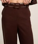 Pantalón wide leg de cintura alta color marrón, confeccionado en viscolino con 15% de lino, con trabillas en la cintura y vieses contrastantes en las barras. Incluye cinturón de tejido con hebilla metalizada de efecto martillado.