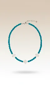 Collar corto de cuentas facetadas color turquesa con tres dijes de trébol de nácar y cierre de acero.