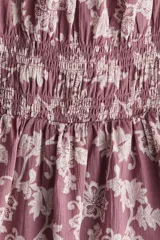 Vestido corto color lila con estampado floral en blanco, escote cuadrado con volados, mangas cortas abullonadas con elástico y cuerpo fruncido.