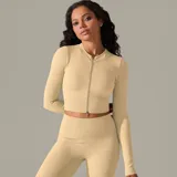 Campera deportiva color beige, de corte ajustado y tejido acanalado. Presenta cierre frontal completo y mangas largas.