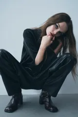 Pantalón de cuero negro de tiro medio, con pinzas delanteras, bolsillos laterales ocultos y corte holgado.