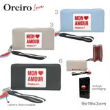 Billetera celeste con cierre de cremallera, detalle de parche con la frase "Mon Amour" y tira de agarre con diseño a rayas.