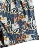 Short de baño azul con estampado floral en tonos blanco, naranja y verde. Tiene elástico en la cintura, cordón ajustable, bolsillos laterales y un bolsillo trasero con botón. Marca Von Braun.
