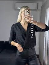 Blusa negra con estampado de lunares blancos, escote en V cruzado, mangas 3/4 abullonadas y hombreras. Talle único abarca hasta L.