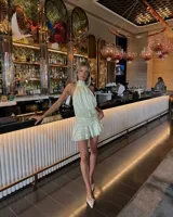 Vestido corto celeste con finas rayas verticales blancas, cuello halter fruncido y cintura y ruedo con frunces.