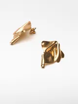 Par de aros metálicos dorados con forma irregular y relieve. Cierre con broche a presión.