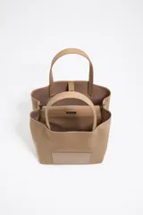 Bolso de mano Bimba y Lola modelo Chihuahua L, color marrón, con doble asa de mano y asa bandolera de tejido. Cierre con botón de presión, logo metálico y acabados plateados.