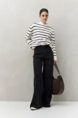 Pantalón de jean negro de calce ultra wide leg, tiro alto y silueta amplia desde la cadera hasta el bajo. Diseño clásico de cinco bolsillos y cierre con botón metálico y cremallera.
