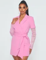 Vestido corto tipo blazer color rosa, con escote cruzado, cinturón y mangas largas de strass.