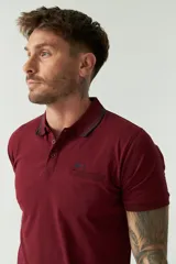 Remera polo negra de manga corta con cuello clásico, cierre de botones, bolsillo en el pecho y logo estampado.