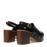 Sandalia de mujer con capellada de cuero negro, diseño cerrado en la punta (peep-toe) y pulsera ajustable con hebilla dorada en el tobillo. Posee una plataforma y taco alto de madera oscura, con detalles de tachas metálicas doradas en la unión entre la capellada y la plataforma.