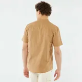 Camisa color beige de manga corta con cuello mao y cierre frontal con botones.