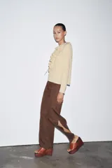 Camisa color beige de algodón con escote en V y volantes. Tiene mangas largas con botón en los puños y cierre con lazos en el frente.