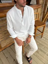 Camisa blanca de lino con cuello mao, manga larga con puños abotonados y cierre parcial con botones de madera.