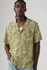 Camisa de manga corta color verde oliva con estampado floral blanco, cuello tipo camp y bolsillo en el pecho.