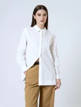 Camisa blanca de corte recto, con cuello clásico, cierre frontal con botones y mangas largas con puños abotonados.