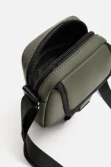 Bandolera vertical negra de acabado engomado con compartimento principal con cierre de cremallera y bolsillo interior plano. Bolsillo frontal con cierre de hebilla de liberación rápida. Asa de hombro ajustable y extraíble.