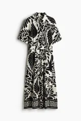 Vestido midi camisero con estampado floral en blanco y negro, cuello camisero, botonadura frontal y mangas cortas. Incluye cinturón extraíble para atar.