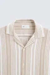 Camisa de hombre a rayas verticales color beige y blanco, de corte relaxed fit, manga corta y cuello bowling.