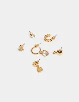 Set de seis aros dorados con diferentes diseños: aros tipo botón con forma de corazón con strass, aro tipo botón con strass, aro tipo botón con dos corazones, aro tipo argolla con tres corazones, aro tipo argolla con dije de corazón con strass y aro tipo botón con dije de corazón.