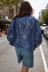 Cazadora azul de cuello solapa y manga larga. Tiene bolsillos de parche en el delantero y cierre frontal con botones.